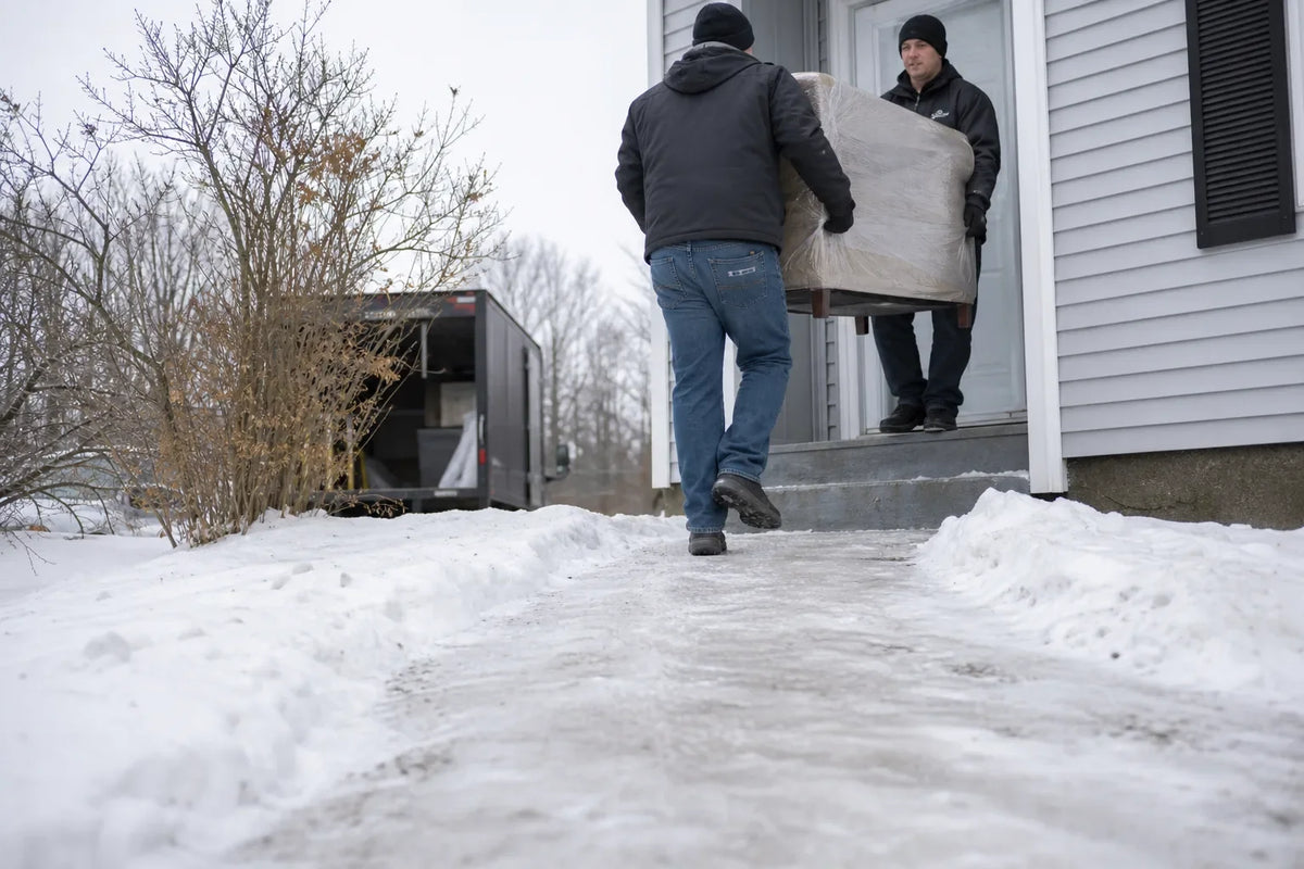 Furniture delivery truck parked on icy street with snow-covered sidewalks in a residential neighborhood during winter