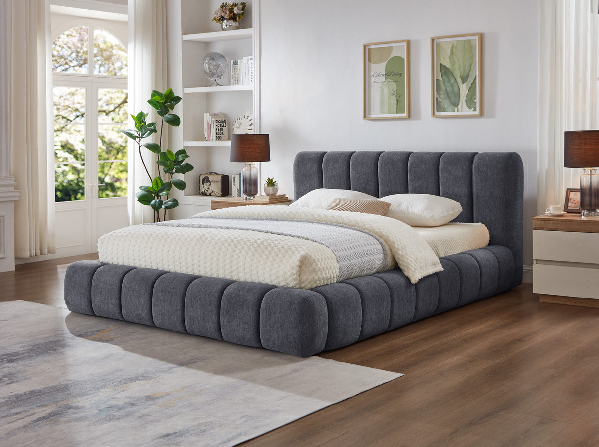 Grey Fairview Platform Bed seen from the side with plush vertical panels and bedside table with lamp
