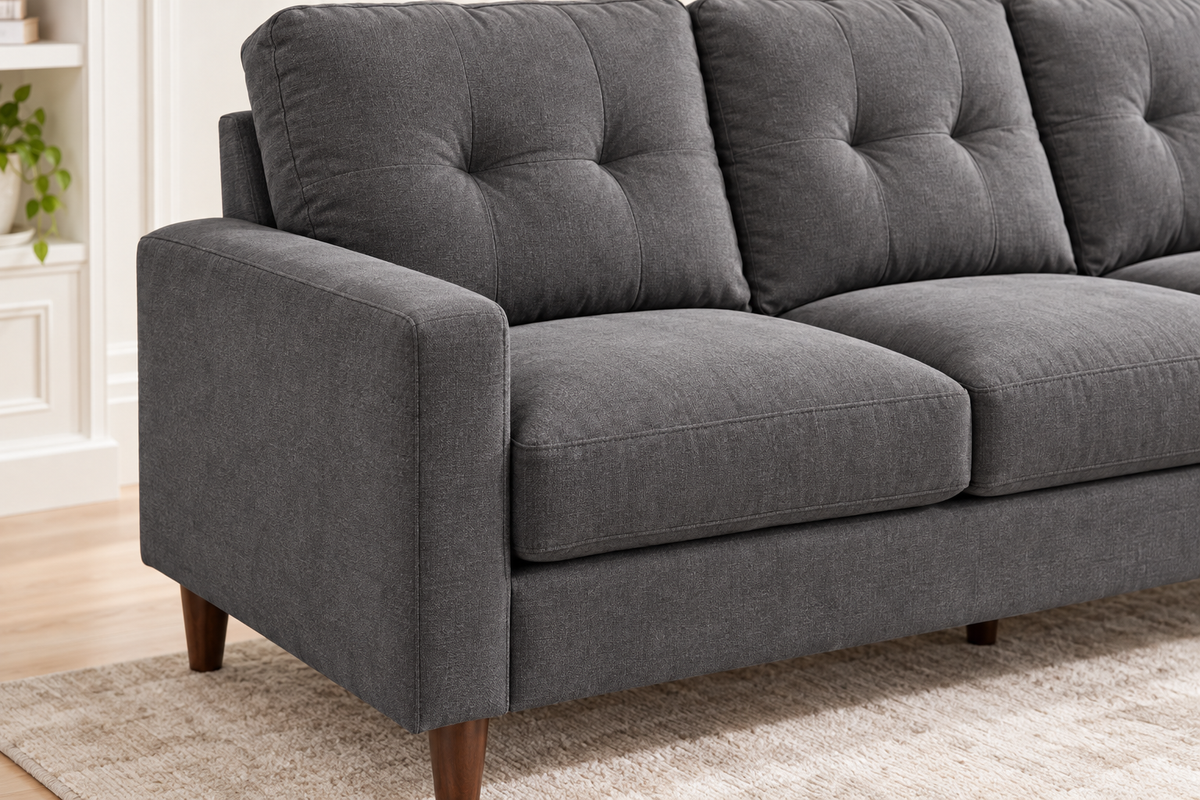 Close-up of the Bella dark grey sofa showing fabric upholstery, button-tufted back cushions, box arm and wood leg.