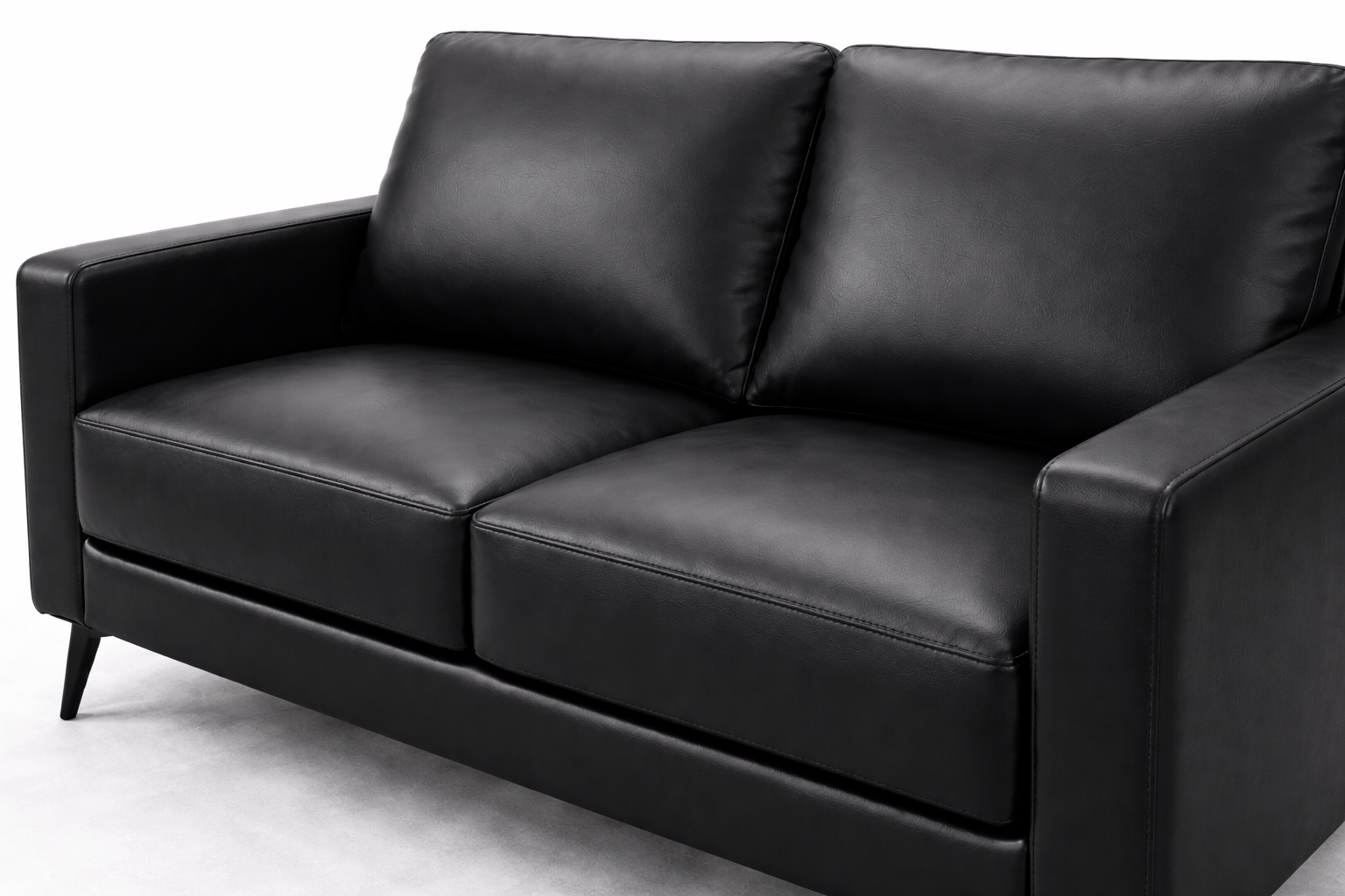 Close-up angled view of black leatherette loveseat showing smooth texture and stitching detail