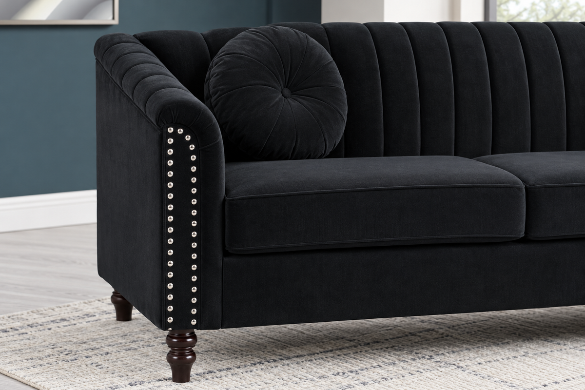 Close-up of the John black sofa showing the rolled arm, decorative nailhead trim, vertical upholstery detailing and turned leg.