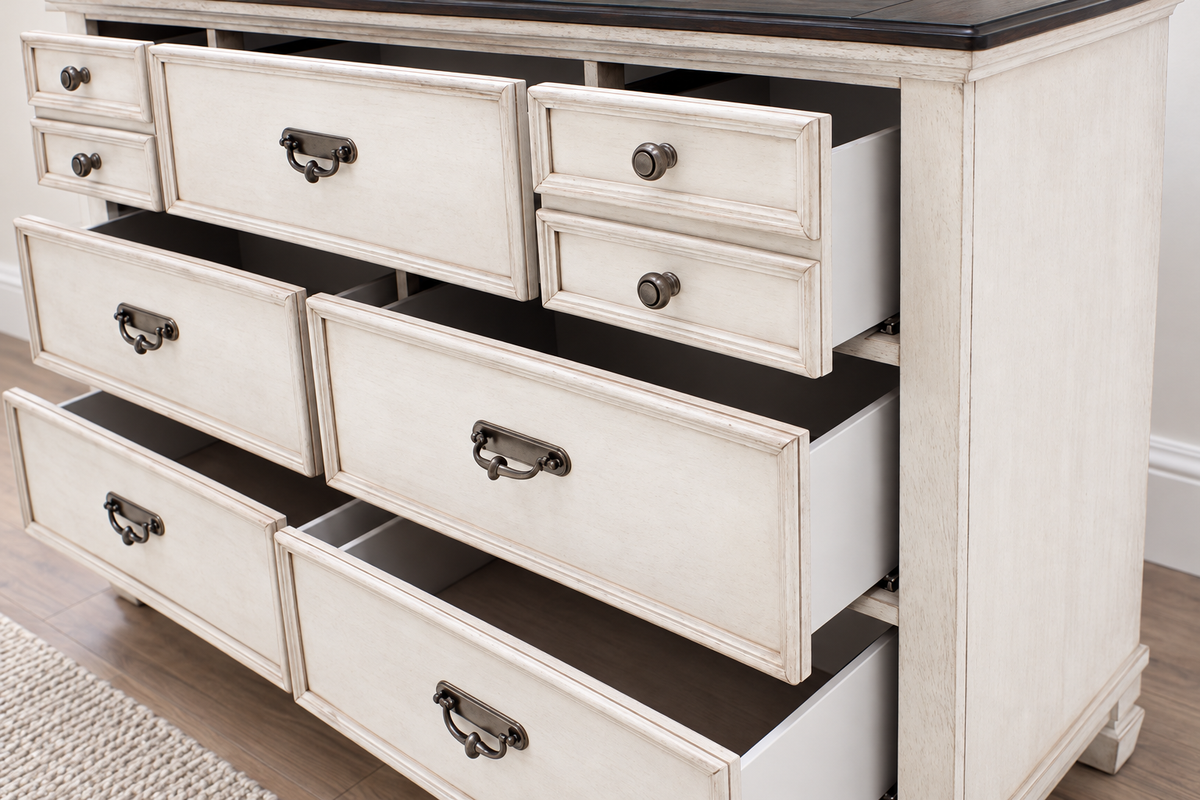 Detail of the Natasha antique white dresser showing open drawers, metal handles and the dark top.