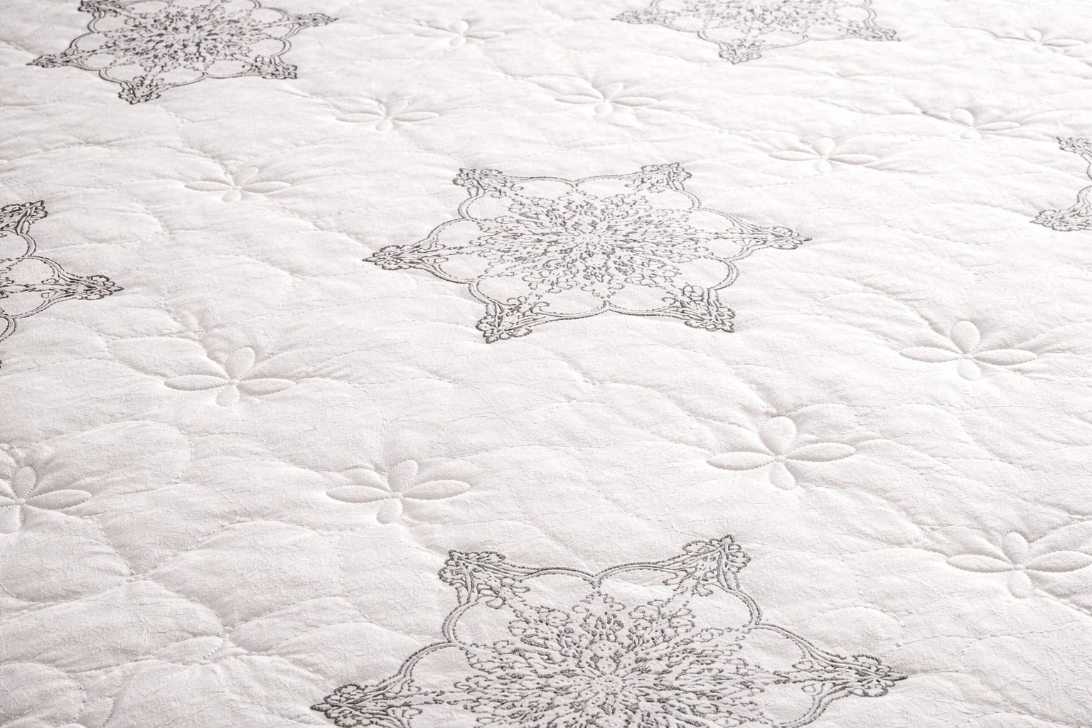 Close-up of Perfection mattress top showing quilted white fabric with floral stitching and soft textured surface
