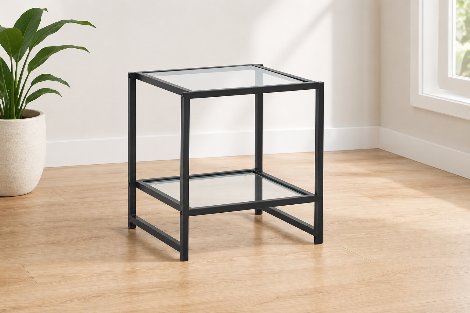 Black metal side table with clear glass top and lower glass shelf in a modern neutral room.