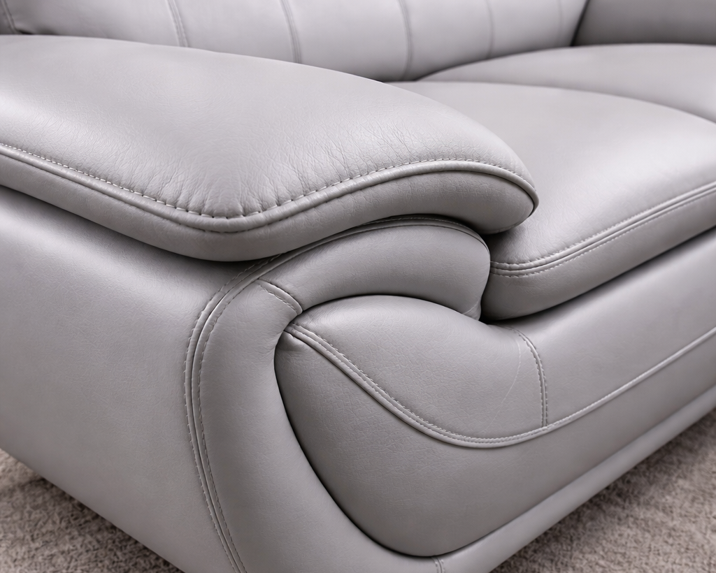 Close-up angled view of grey leather sofa showing leather texture and stitching detail