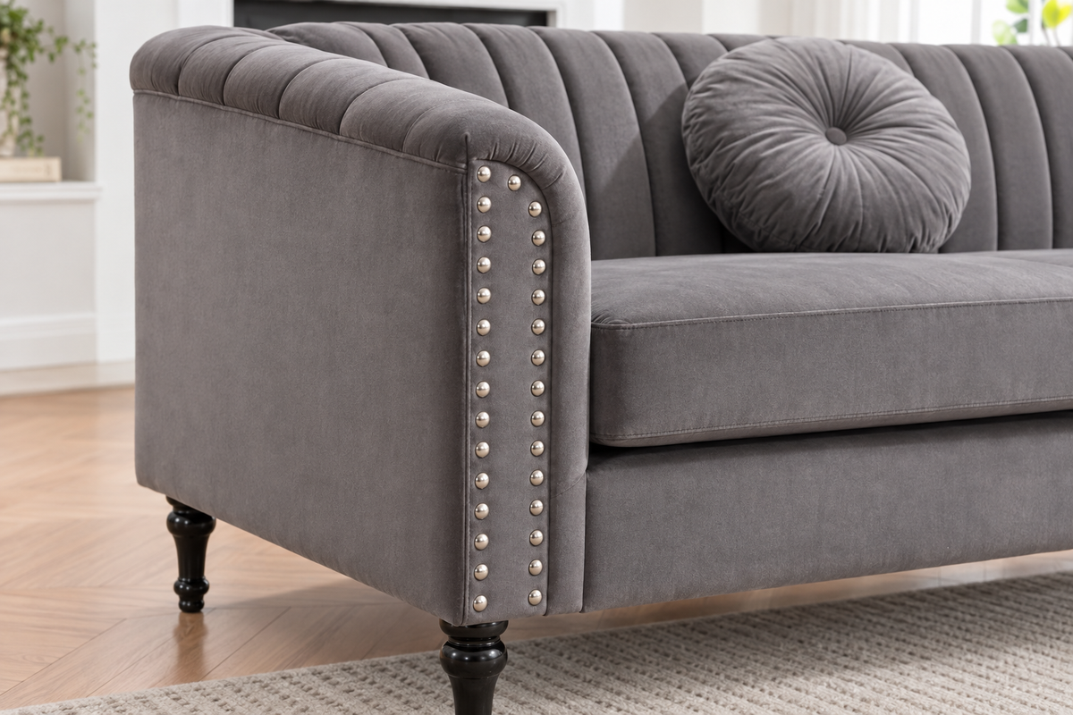 Close-up of the John grey sofa showing the rolled arm, decorative nailhead trim, vertical upholstery detailing and turned leg.