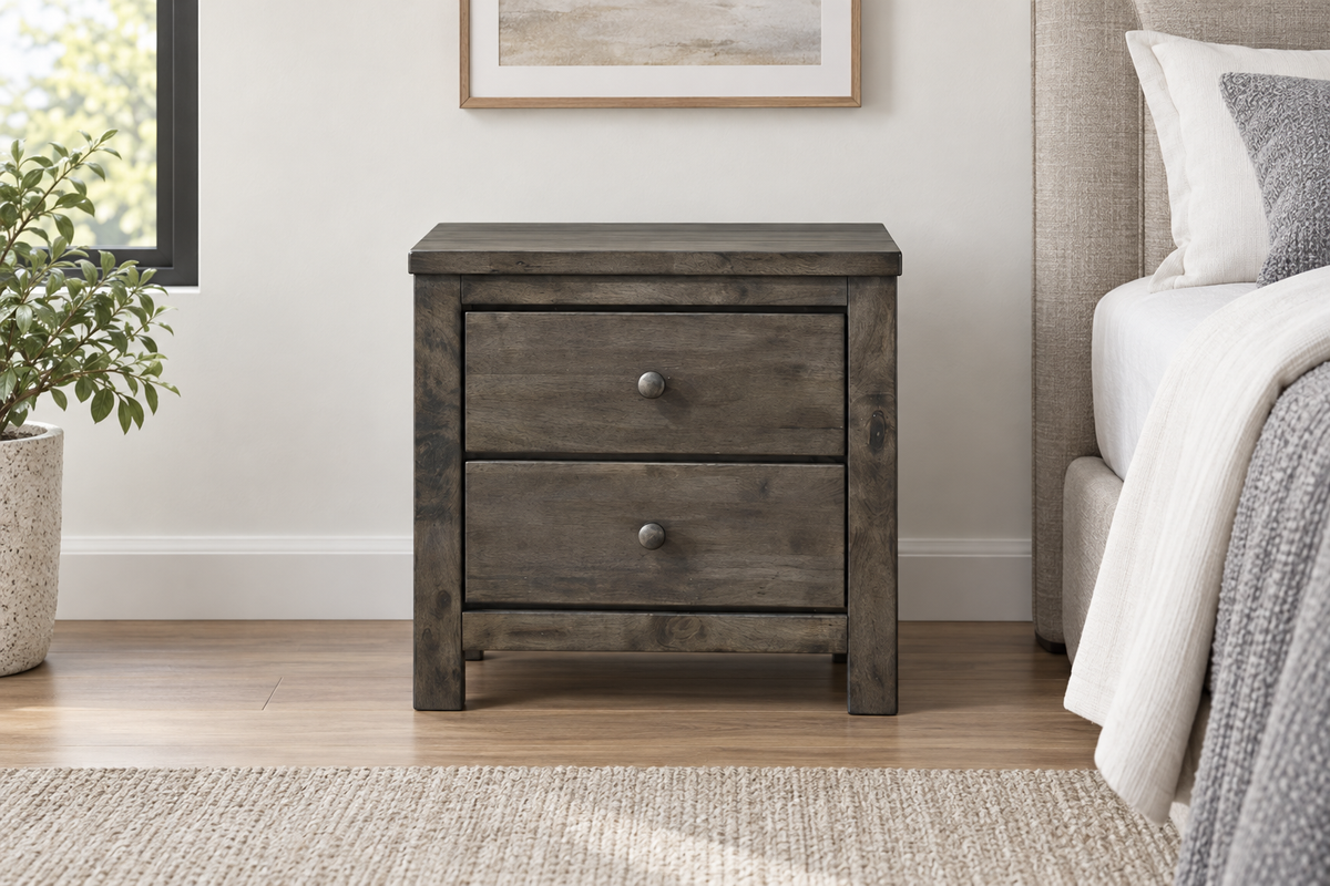 Margaret grey two-drawer nightstand with round knobs, viewed from the front beside a bed.