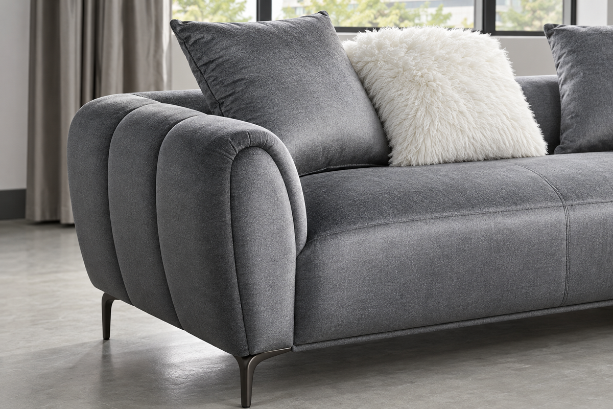 Close-up of the Sam grey sofa showing the rounded channelled arm, upholstery texture, accent cushions and slim leg.